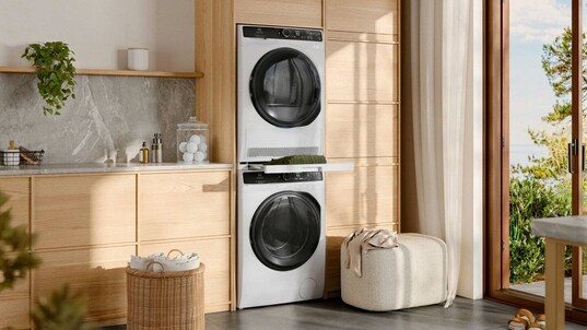 Στεγνωτήριο electrolux συρραμμένο πάνω από ένα πλυντήριο ρούχων σε ένα ηλιόλουστο πλυντήριο.