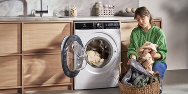Woman in green sweater loading washing machine