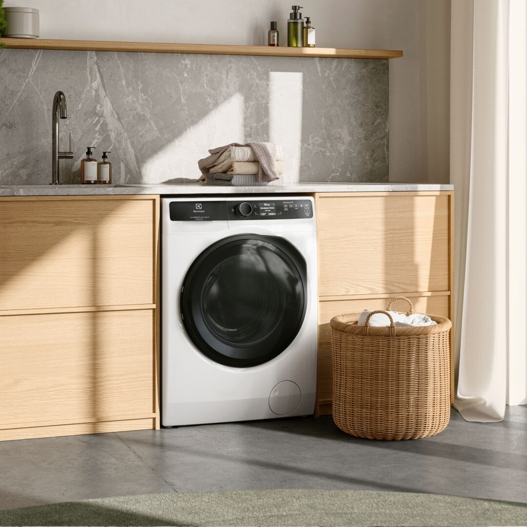 Φωτεινό δωμάτιο με πλυντήριο ρούχων electrolux κάτω από έναν πάγκο.